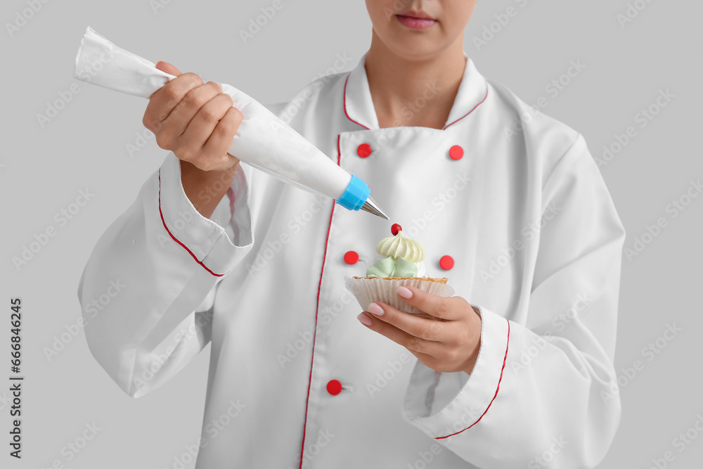 Female confectioner decorating tasty cake on white background