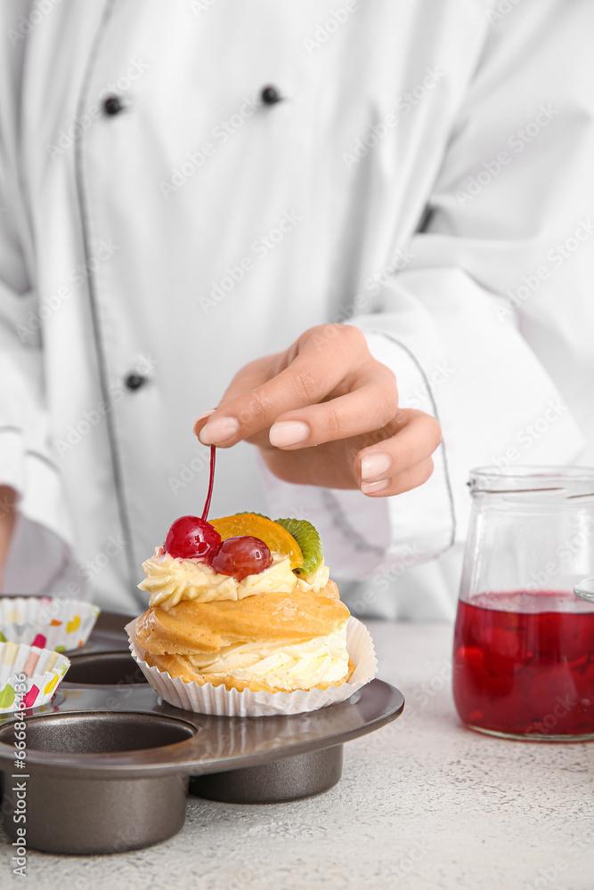 Female confectioner decorating tasty cake on white background