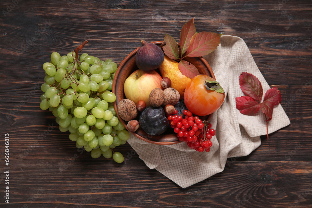 Bowl with different fresh fruits on wooden background