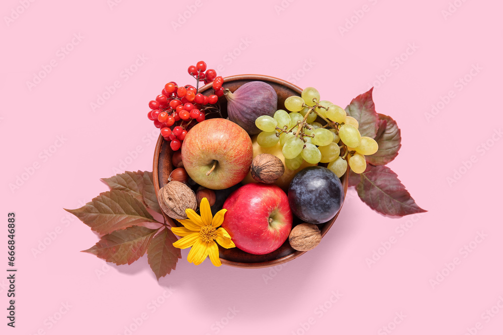 Bowl with different fresh fruits and nuts on pink background