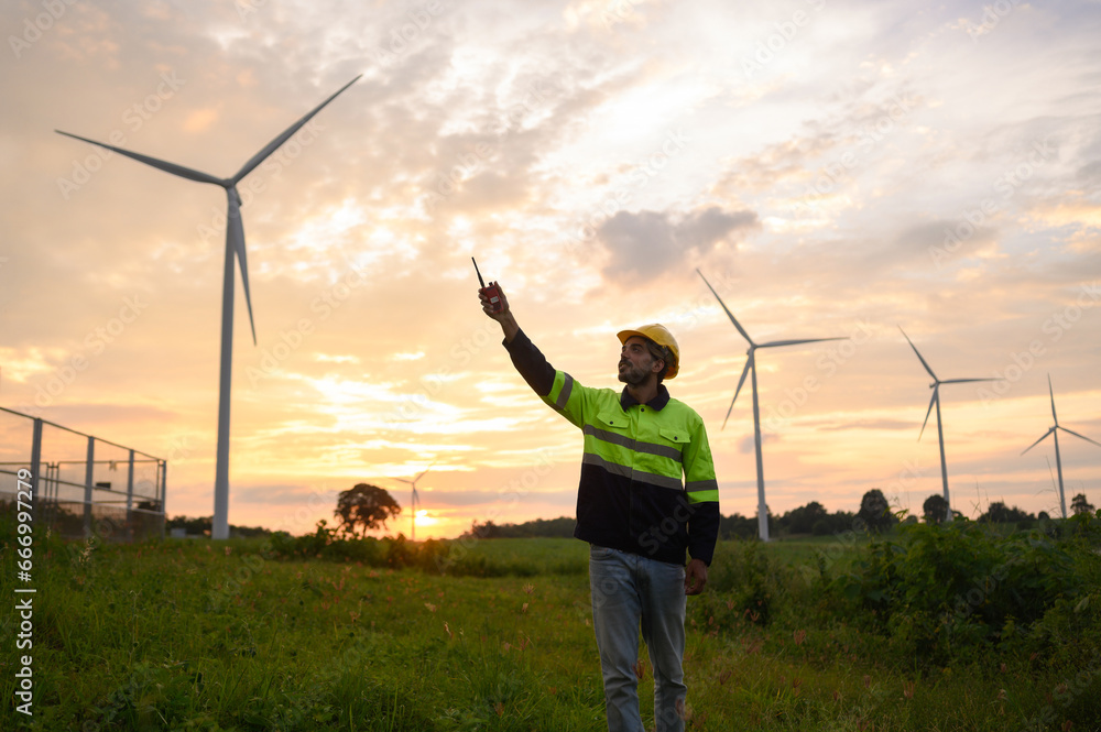 Portrait of engineer wearing yellow vest and white hat on site at wind farm or solar cell farm and energy sustainable energy concept