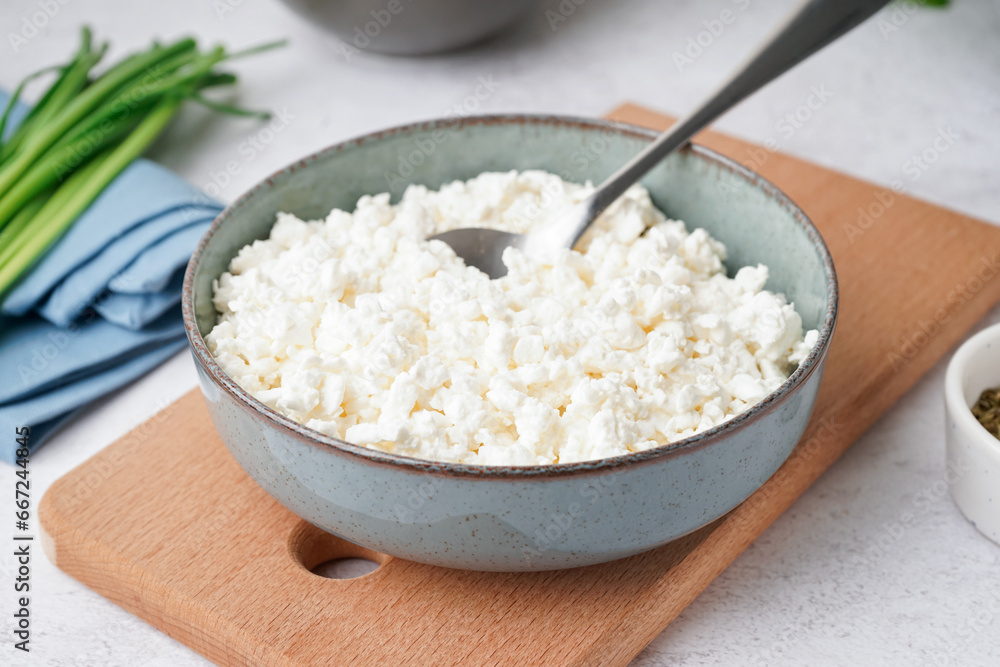 Bowl with tasty cottage cheese on light background