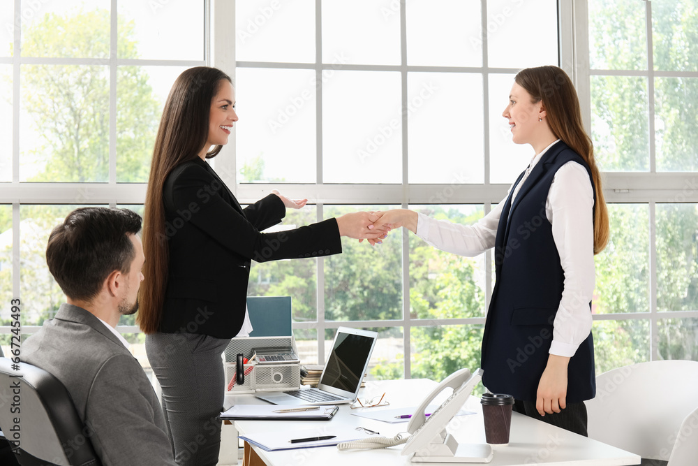 Human resources manager shaking hands with female applicant in office