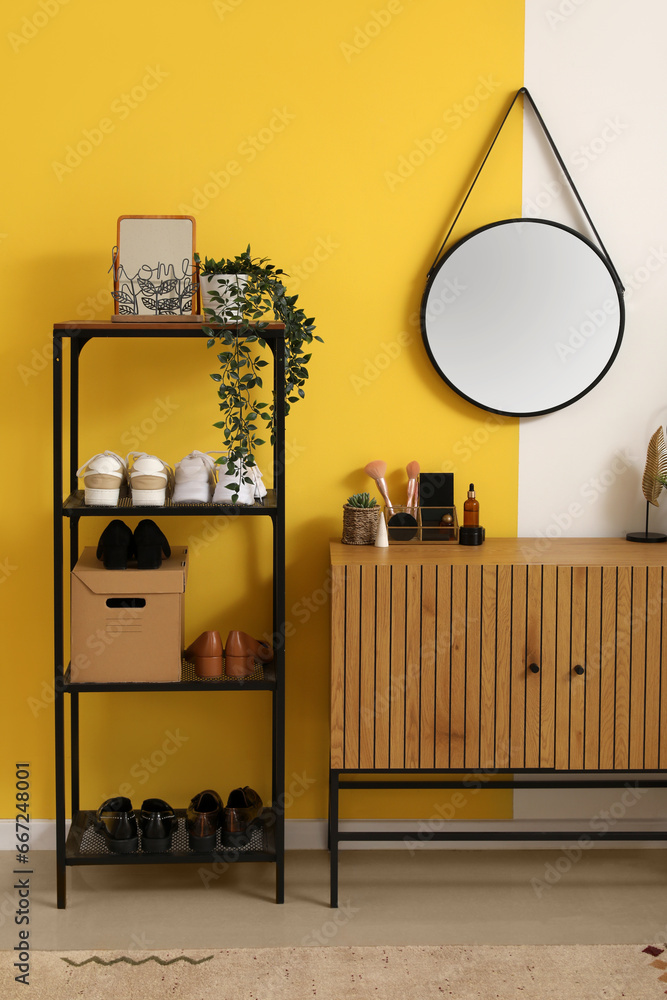 Interior of stylish hallway with mirror, wooden cabinet and shoe stand