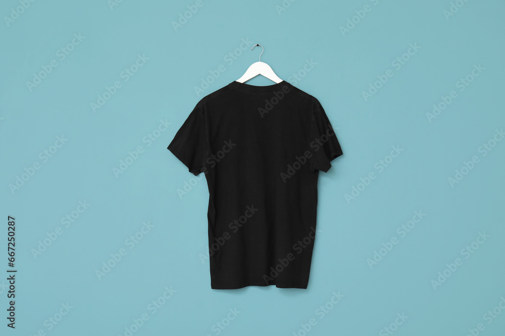 Stylish black t-shirt hanging on blue background