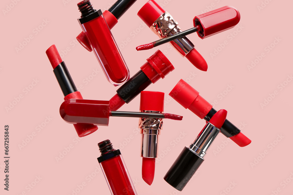 Different red lipsticks flying on pink background