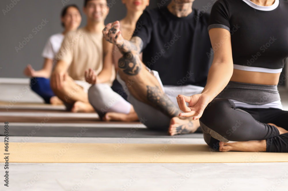 Group of sporty young people meditating in gym, closeup