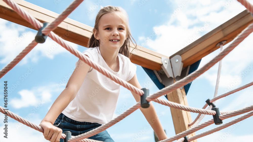 Happy child climbing the net in the playground