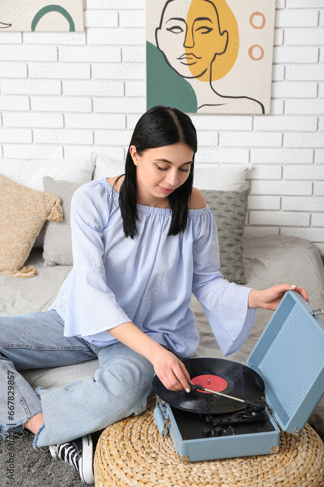 Young woman with record player in bedroom