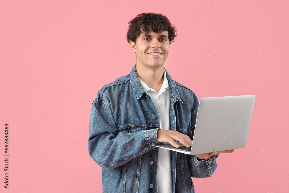 Male programmer working with laptop on pink background