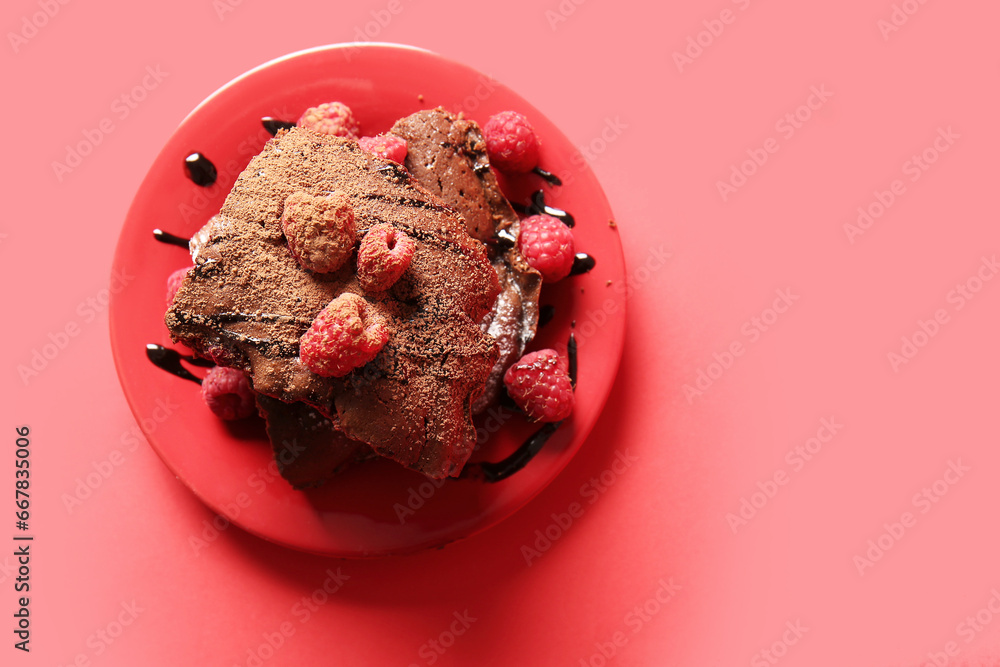 Plate with pieces of raspberry chocolate brownie on red background