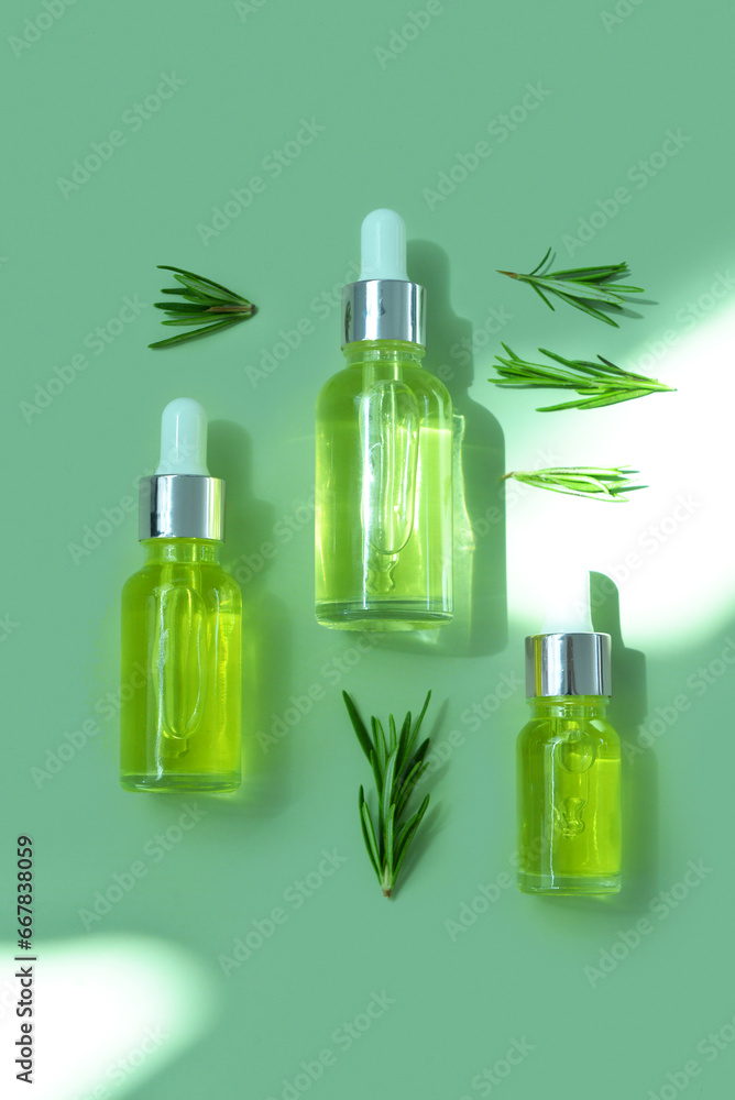 Bottles of healthy essential oil with herbs on green background