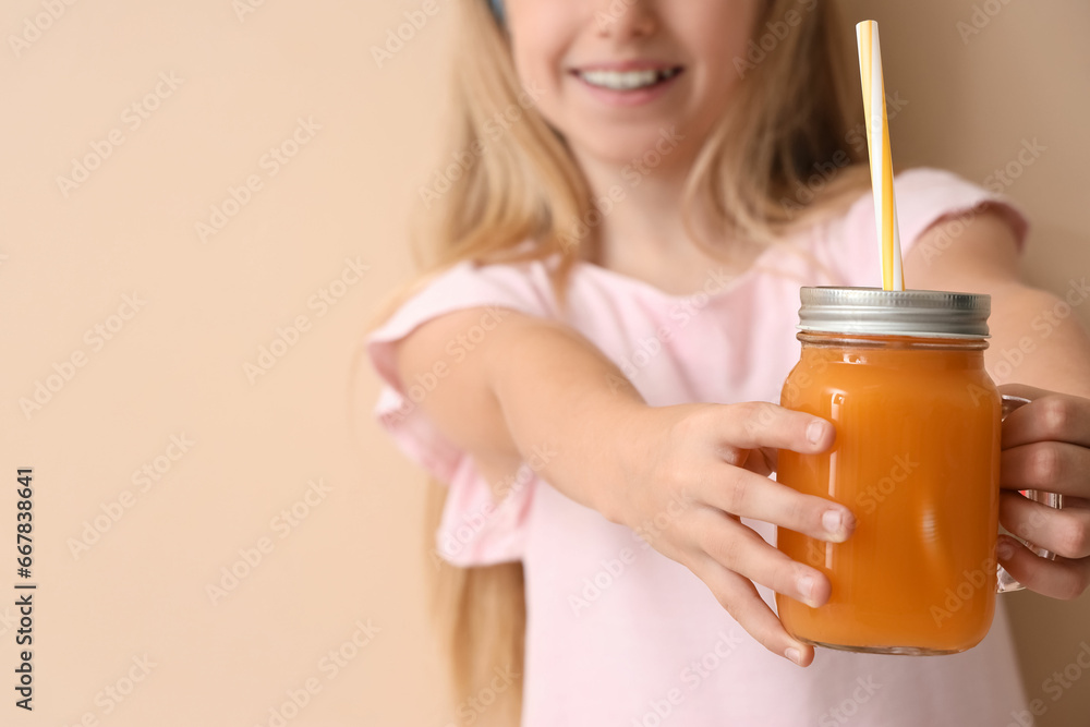 Little girl with glass jar of juice on beige background, closeup