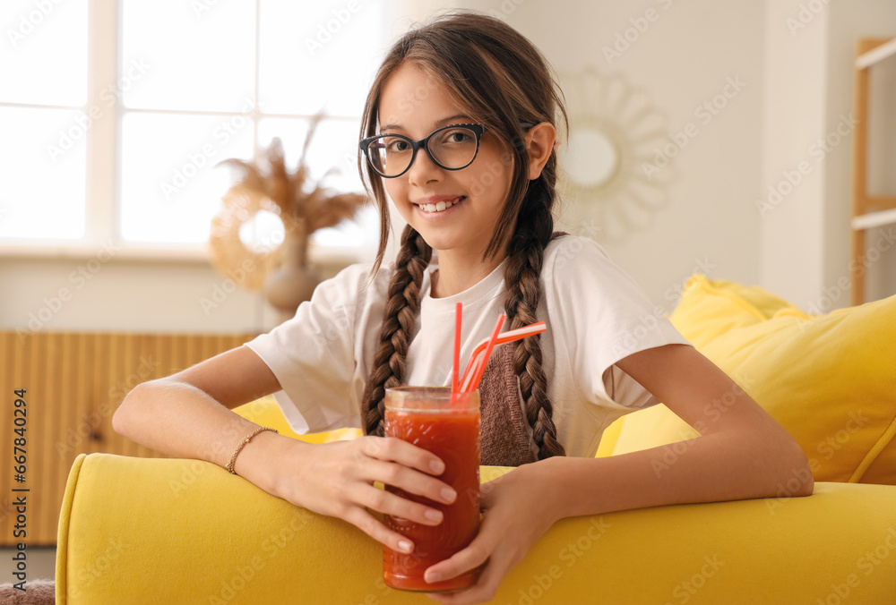 Little girl with glass of red juice at home