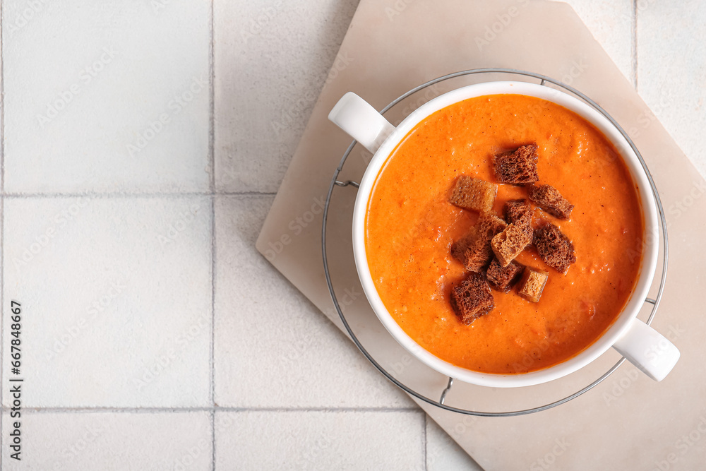 Pot of tasty cream soup with croutons on white tile background