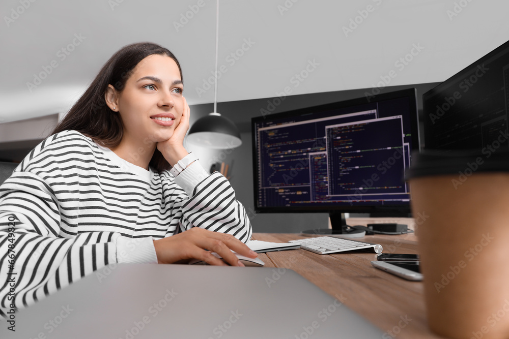 Pretty young female programmer working in office