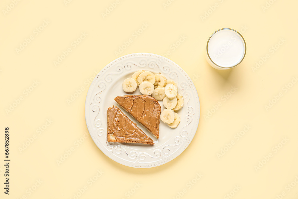 Plate of cut toast with peanut butter and banana on yellow background