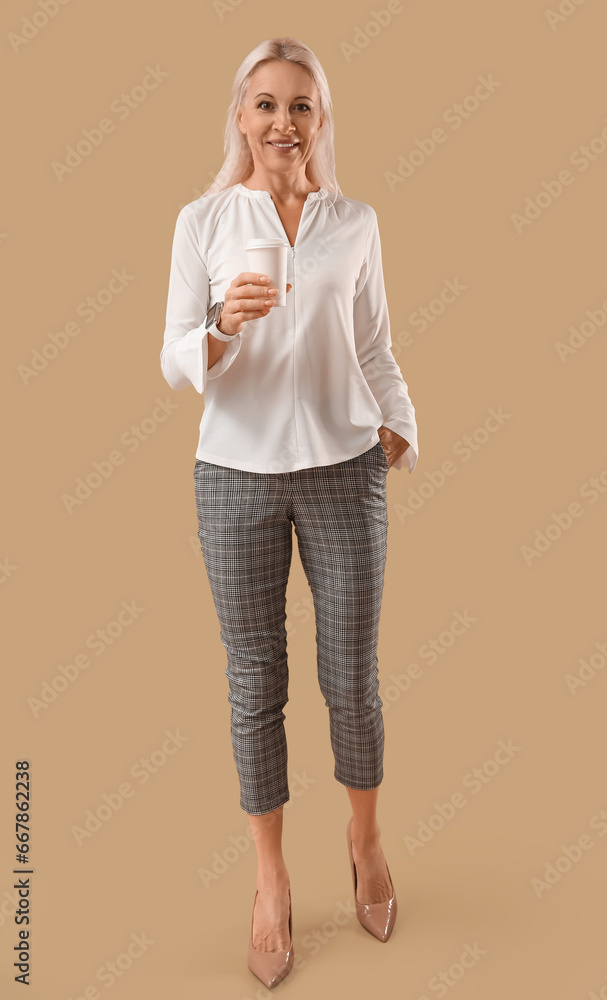 Mature woman with cup of coffee on brown background