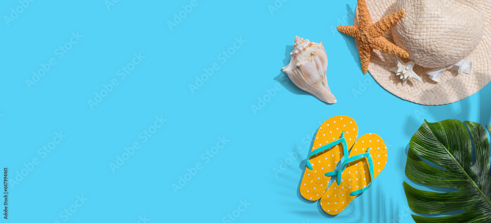 Summer concept with a straw hat, starfish, beach sandals and shell overhead view