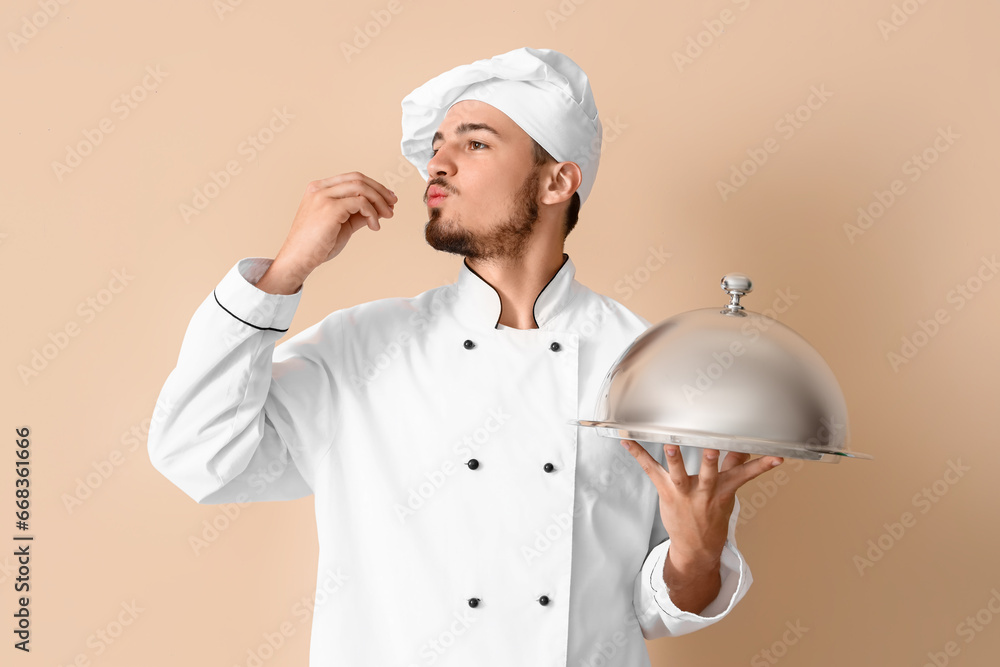 Male chef with cloche on beige background