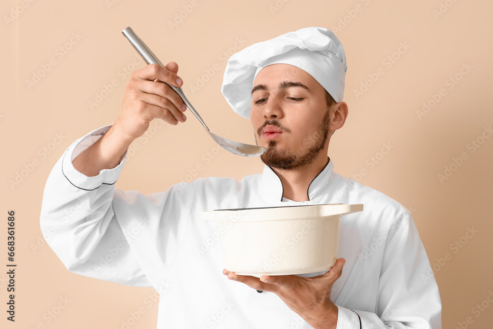 Male chef with ladle and cooking pot on beige background