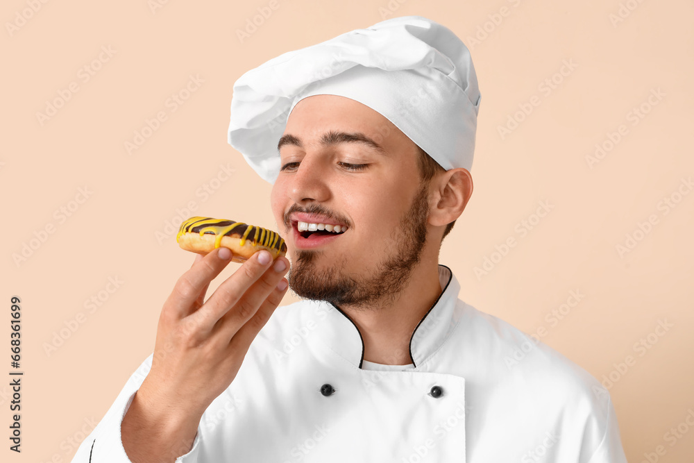 Male chef with tasty doughnut on beige background, closeup