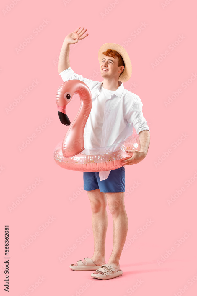 Young man with swim ring on pink background