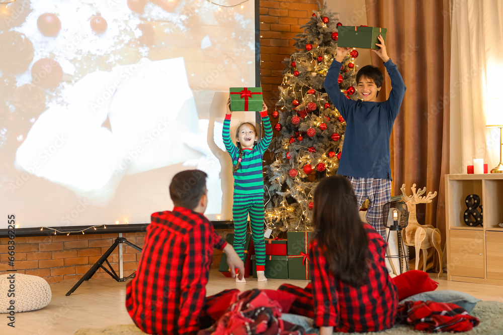 Happy family with gifts watching Christmas movie at home