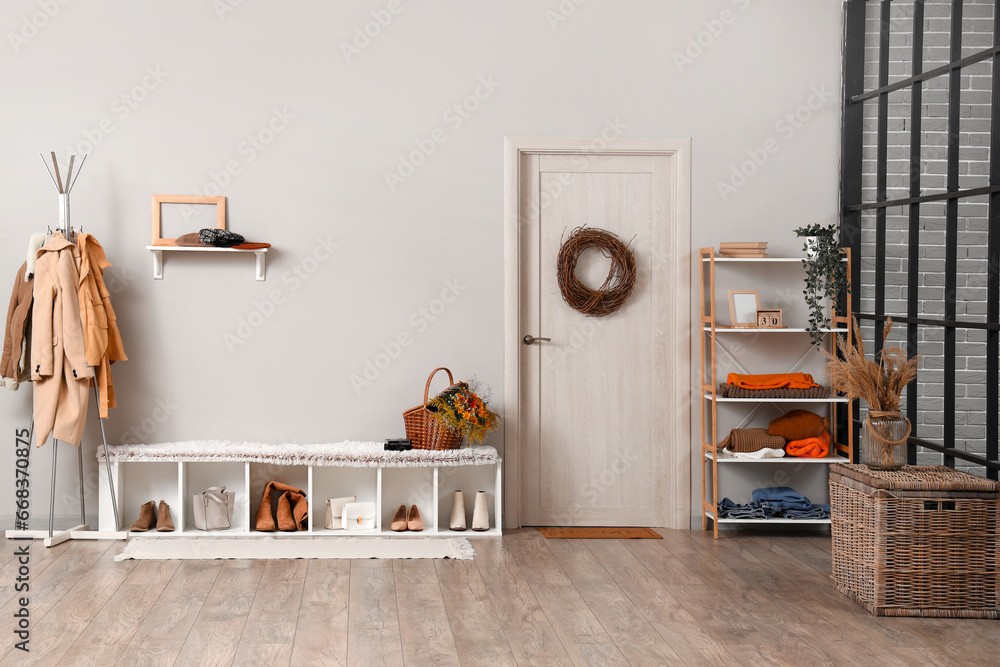 Interior of modern hallway with stylish clothes, shoes and autumn decorations