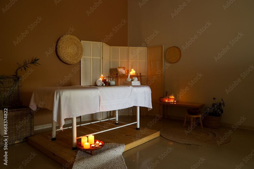 Interior of dark spa salon with couch and burning candles