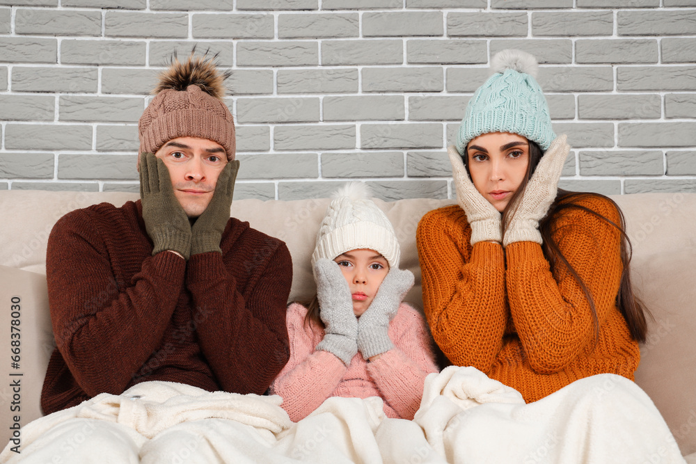 Frozen family in warm clothes at home with lack of heating