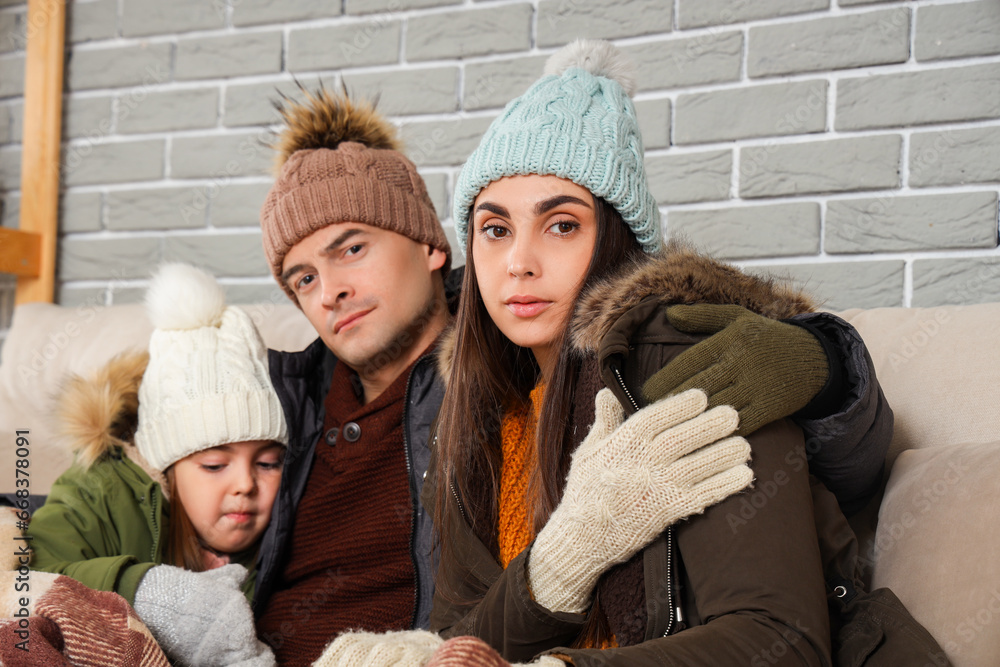 Frozen family in warm clothes at home with lack of heating