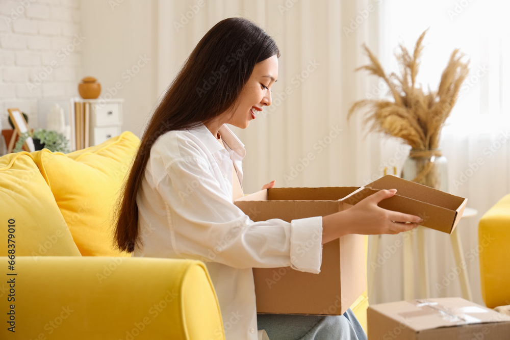 Young Asian woman with parcel at home