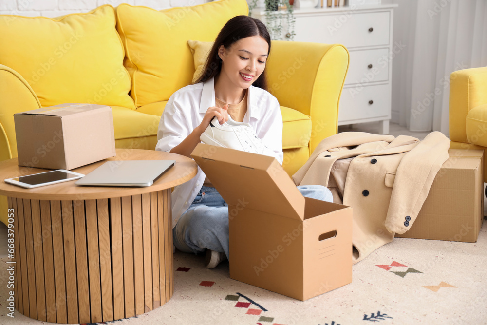 Young Asian woman with new shoes from parcel box at home