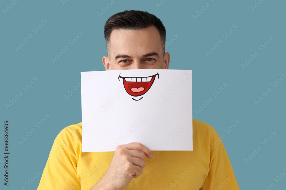 Handsome man with paper smile on blue background, closeup