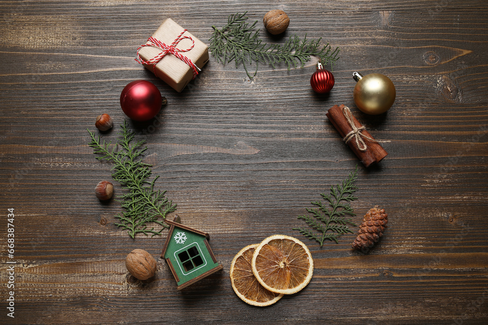 Frame made of coniferous branches with food, gift and Christmas balls on dark wooden background