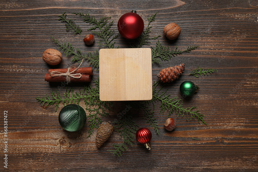 Blank board with Christmas balls, coniferous branches and food on dark wooden background