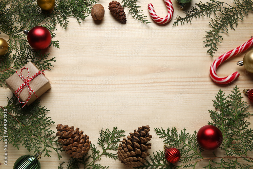 Frame made of Christmas branches, decor and gift on light wooden background