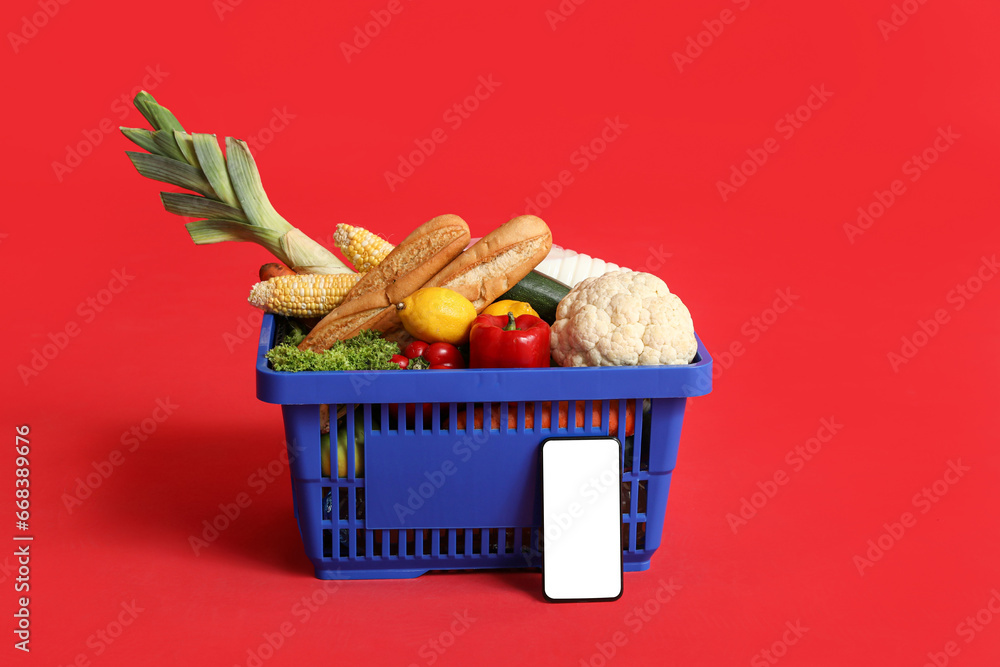 Shopping basket full of food with mobile phone on red background