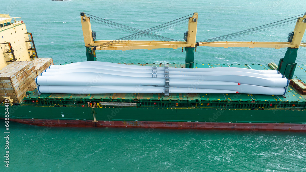 Wind Turbine on Ship, Transportation of blades for wind turbines on a cargo ship. Heavy load carrier on cargo ship loaded with Electric Wind Turbine Blades.