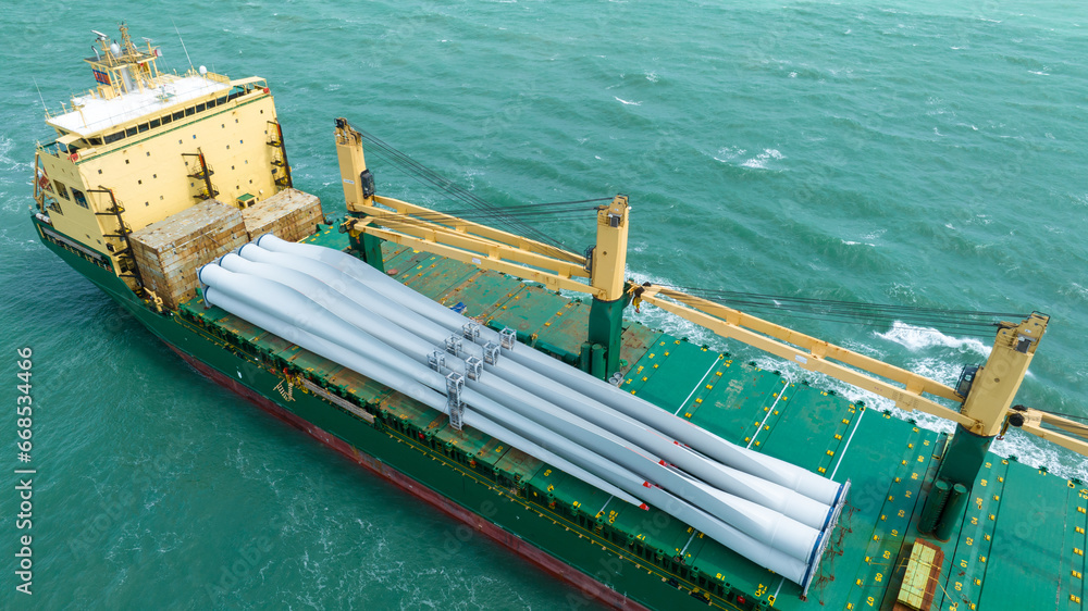 Wind Turbine on Ship, Transportation of blades for wind turbines on a cargo ship. Heavy load carrier on cargo ship loaded with Electric Wind Turbine Blades.