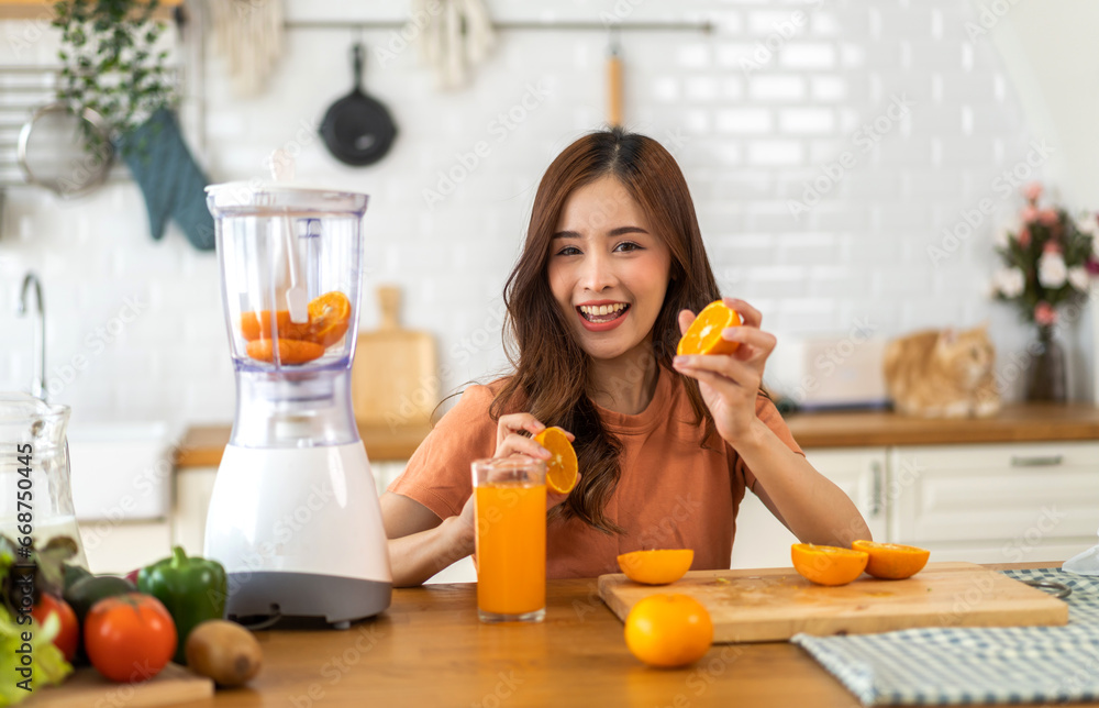 Portrait of beauty healthy asian woman making orange fruit smoothie with blender.girl preparing cooking detox cleanse with fresh orange juice in kitchen at home.health, vitamin c, diet, healthy drink