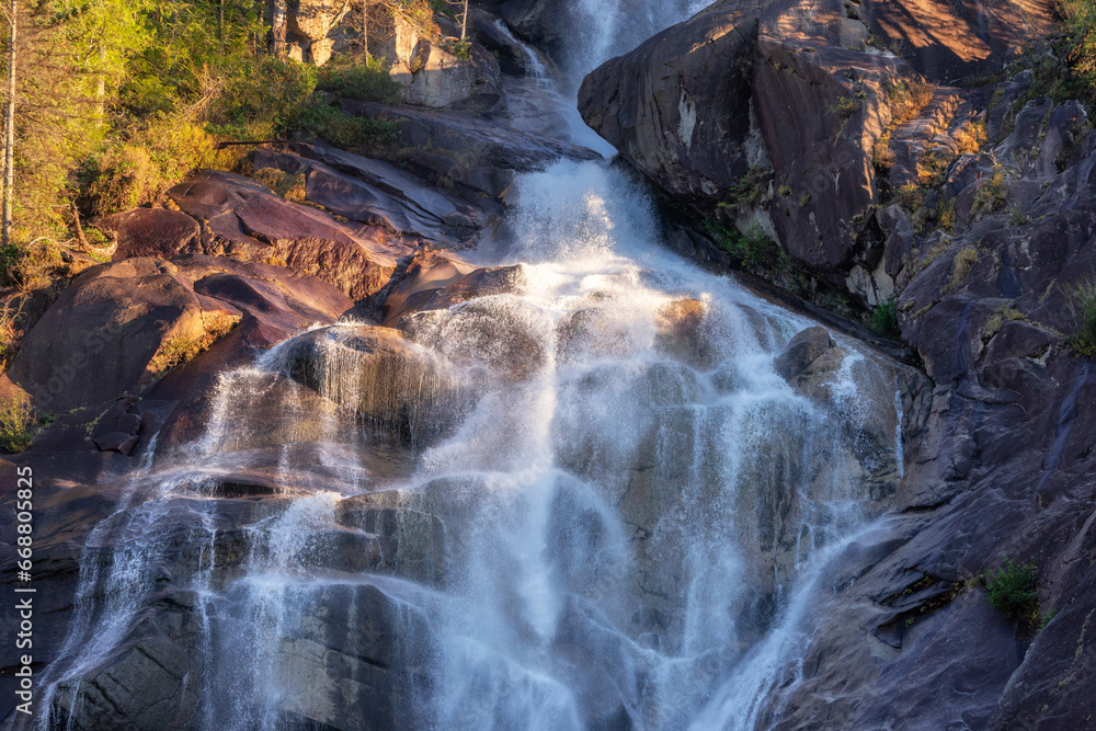 Waterfall rushing down the rocks. Sunset. Shannon Falls, Squamish, BC, Canada.