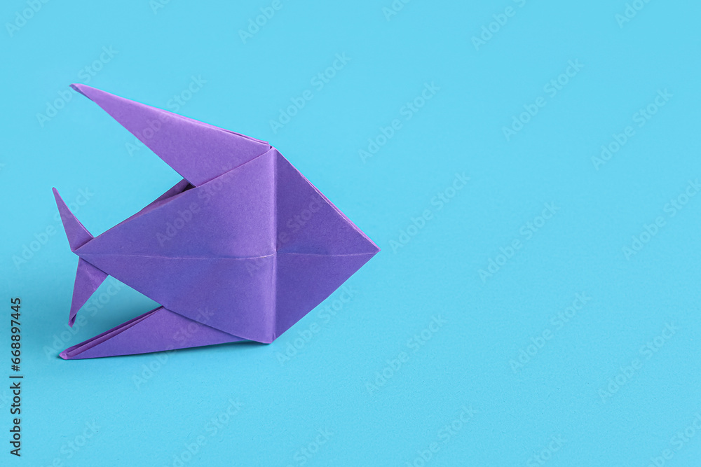 Purple origami fish on blue background