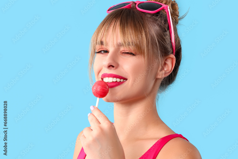 Young woman with lollipop on blue background, closeup