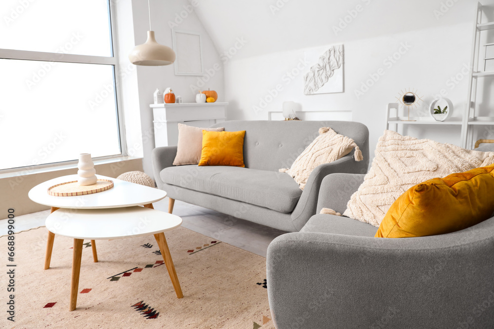 Interior of light living room with sofa, armchair and tables