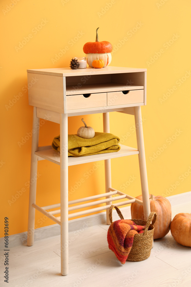 White table with pumpkins near orange wall