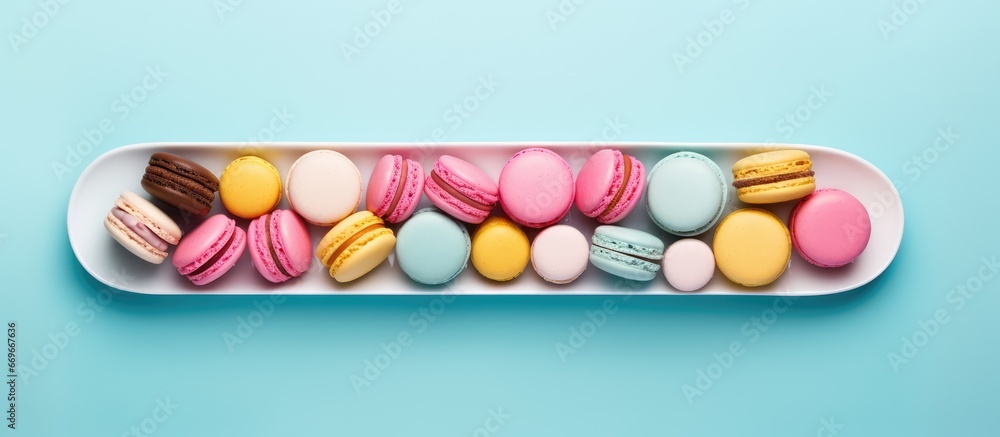 Top view of macaroons dessert arranged in a flat lay composition on a blue background with empty space for text