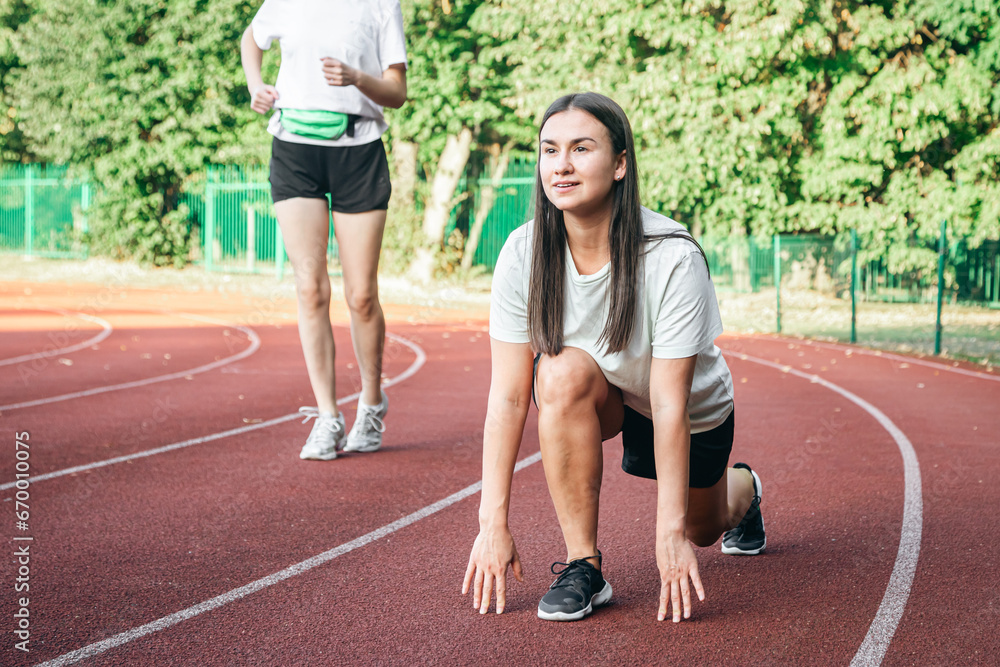 A young woman runner in start position on running track while work out.