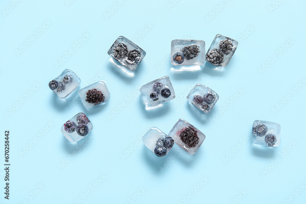 Frozen berries in ice cubes on blue background